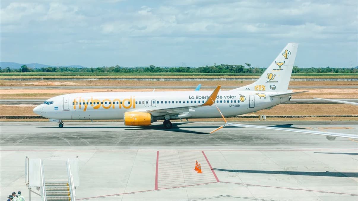 Avião Boeing 737 da companhia aérea argentina Flybondi parado no pátio de um aeroporto, com equipe de solo ao lado de uma escada de embarque