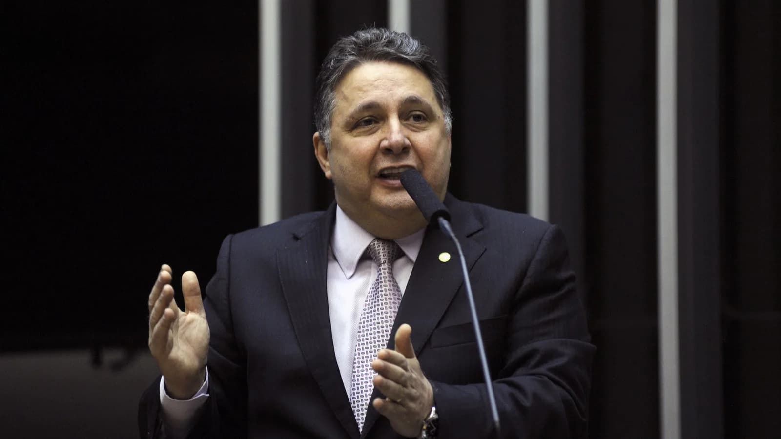 Anthony Garotinho discursa em tribuna com microfone, de terno escuro